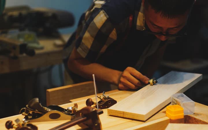 Un artisan travaille une planche sur son établi